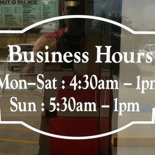 a business hours sign in a window