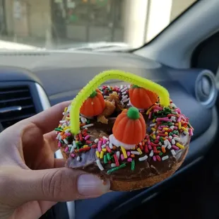 a hand holding a donut decorated with sprinkles