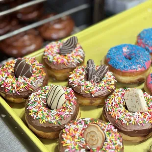 a tray of donuts with chocolate frosting and sprinkles