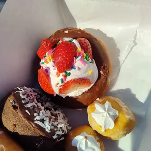 Strawberry cream chocolate, cream puffs and a chocolate coconut donuts.
