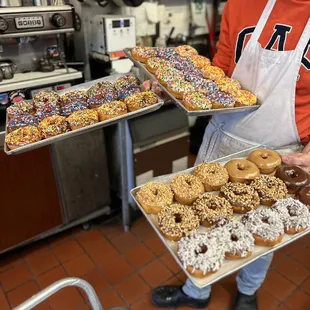 a man holding trays of doughnuts