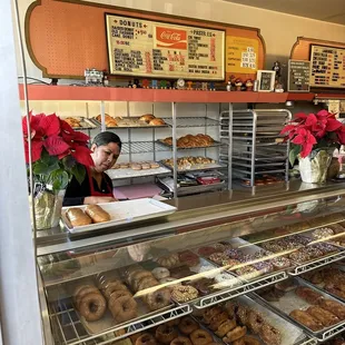 a woman behind the counter of a donut shop