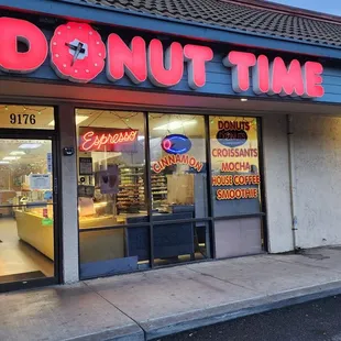 a donut shopfront with neon signs