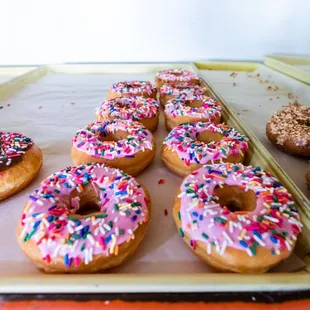 a tray of doughnuts with sprinkles
