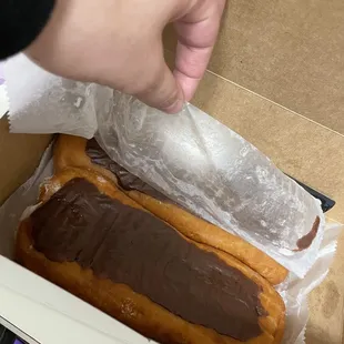 a person putting chocolate on a donut