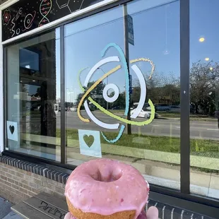 a hand holding a pink donut