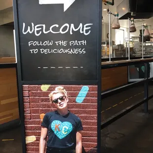 a woman standing in front of a welcome sign