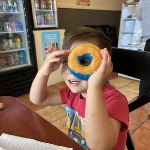 a young boy holding up a donut