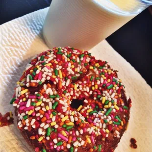 a chocolate donut with sprinkles and a glass of milk