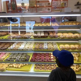 A kid in great happiness amongst freshly made donuts.