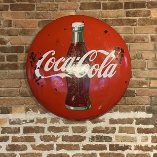 a coca cola sign on a brick wall