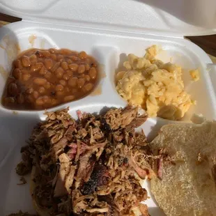 a pulled pork sandwich, beans, macaroni and cheese