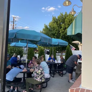 a group of people sitting at tables under umbrellas