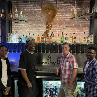 three men standing in front of the bar