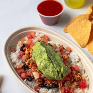 a bowl of rice with guacamole and tortillas