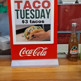 a taco tuesday sign and a bottle of coke