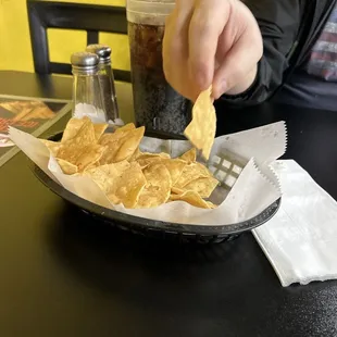 a person dipping a tortilla into a basket