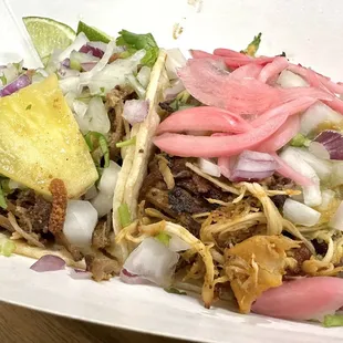 Two street tacos --- one with pork and one with chicken.