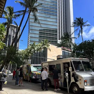 a line of food trucks parked in front of a tall building