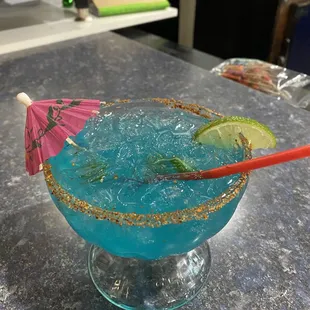 a blue cocktail with a pink umbrella