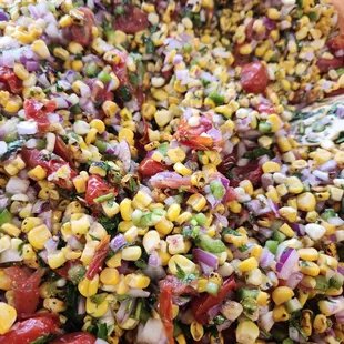 a corn salad with tomatoes and onions