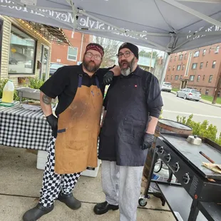 two men standing in front of a bbq