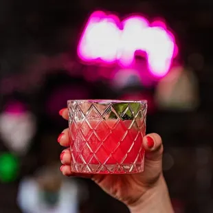 a hand holding a glass of cocktail