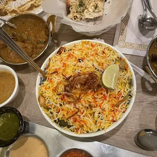 a plate of biryaniza and bowls of curry