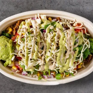A bowl bursting with fresh ingredients, creamy guac, melted cheese, and zesty sauces. Your perfect Mexican flavor fix awaits!