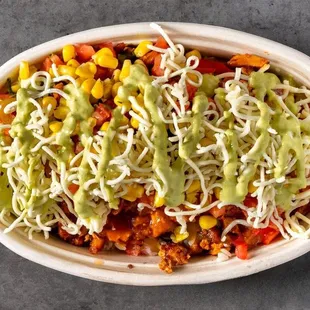 Savor the boldness of Mexican spices in this loaded chicken bowl, topped with melted cheese, corn, and a drizzle of green sauce.