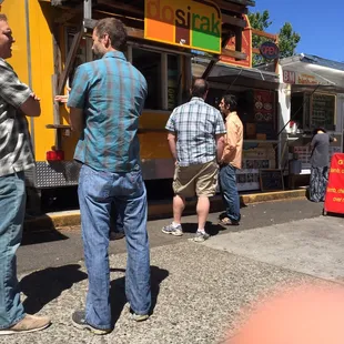 Look for the colorful sign in the row of food carts