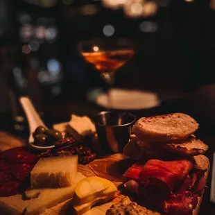a cheese board with meat, cheese, bread, and olives