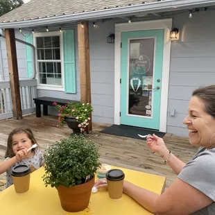 a woman and a child sitting at a table outside a house