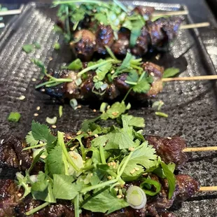 two skewers of meat on a grill