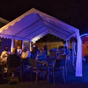 people sitting at tables under a tent
