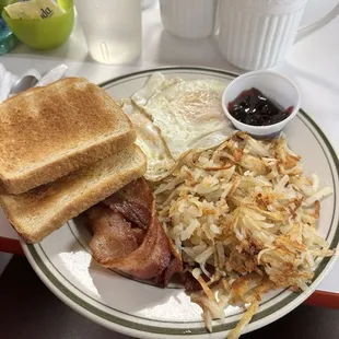Two eggs, hashbrowns, bacon, and toast