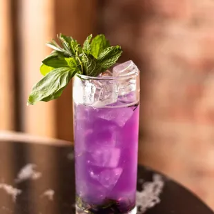 a purple drink with a mint leaf garnish