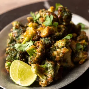 a plate of broccoli with a lime wedge