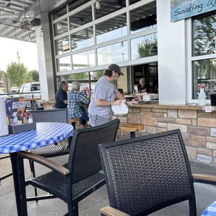 people sitting at tables outside a restaurant