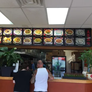 two people standing at the counter of a restaurant