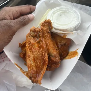 a hand holding a basket of chicken wings