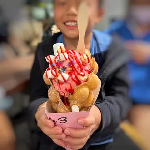 a young boy holding a bowl of ice cream and sprinkles