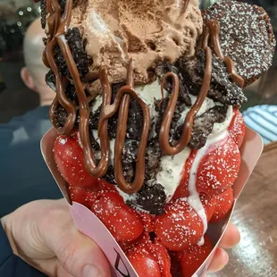 Red velvet waffle with vanilla and chocolate scoops, topped with Oreo cookies, a brownie, and Nutella drizzle.