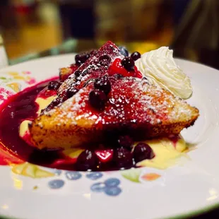 a plate of french toast with blueberry sauce and whipped cream