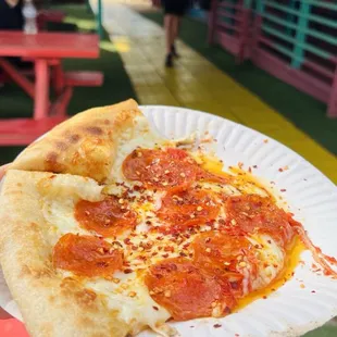 a slice of pepperoni pizza on a paper plate