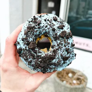 a hand holding a blue frosted donut