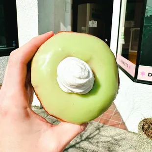 a hand holding a green donut