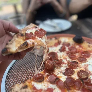 a person taking a slice of pizza