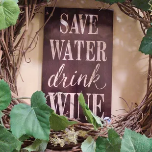 a grapevine wreath with a sign saying save water drink wine