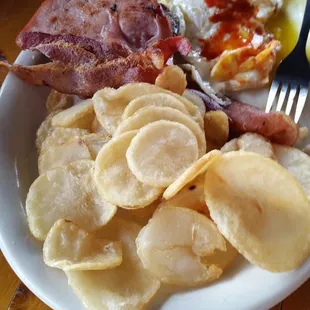 Eggs over medium, home fries, bacon ham and sausage, 2 piece of french toast and biscuits and gravy.